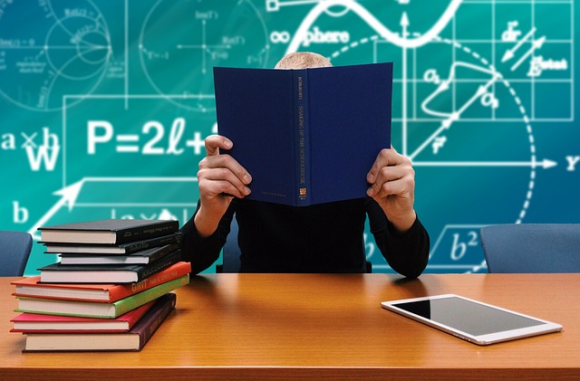 Student sitting at a desk in front of a laptop, reading from a computer